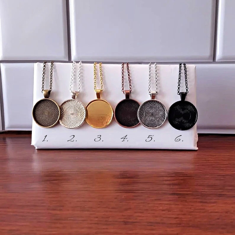 K&ouml;nnte beinhalten: Sechs verschiedene Anh&auml;ngerketten mit runden Metallanh&auml;ngern. Die Anh&auml;nger sind in verschiedenen Ausf&uuml;hrungen, darunter Silber, Gold, Bronze und Schwarz.