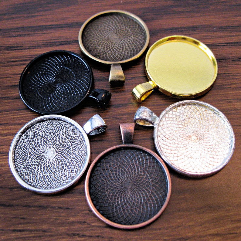 K&ouml;nnte beinhalten: Sechs runde Metall-Anh&auml;nger-Tabletts mit verschiedenen Oberfl&auml;chen. Die Tabletts haben ein dekoratives Wirbelmuster und sind in Silber, Gold, Schwarz und Bronze erh&auml;ltlich.