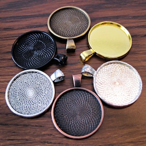 K&ouml;nnte beinhalten: Sechs runde Metall-Anh&auml;nger-Tabletts mit verschiedenen Oberfl&auml;chen. Die Tabletts haben ein dekoratives Wirbelmuster und sind in Schwarz, Silber, Gold, Kupfer und Bronze erh&auml;ltlich.
