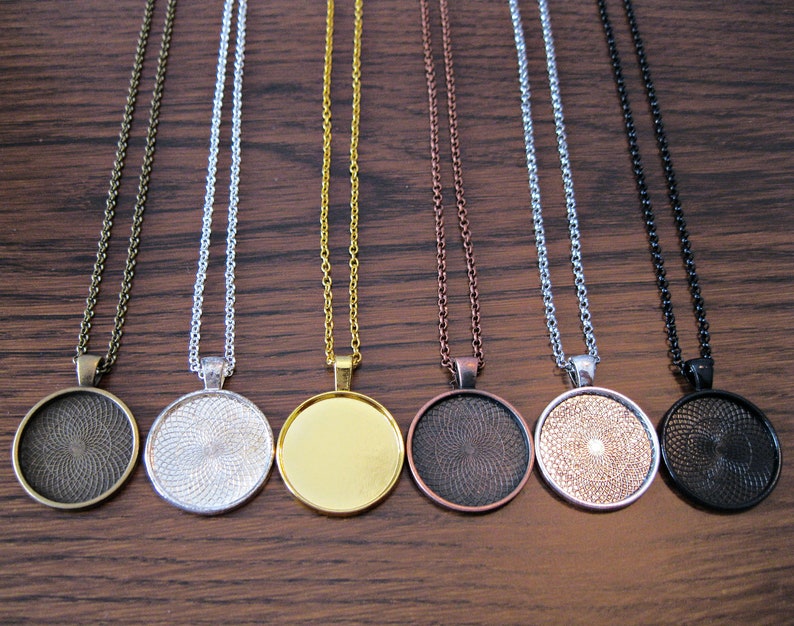 K&ouml;nnte beinhalten: Sieben verschiedene Ketten mit runden Anh&auml;ngern aus Metall. Die Anh&auml;nger sind in verschiedenen Farben, darunter Bronze, Silber, Gold, Kupfer und Schwarz.