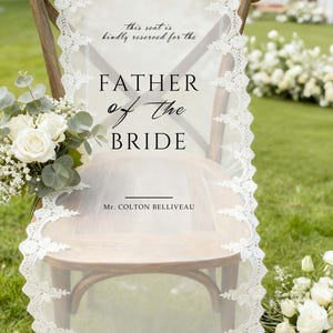 May include: Wooden chair with a white lace overlay, reserved for the Father of the Bride. The overlay features delicate lace trim and text that reads "this seat is kindly reserved for the FATHER of the BRIDE". A bouquet of white roses and greenery is on the left.