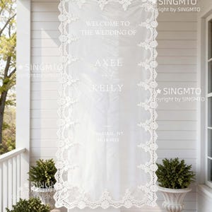 Pode incluir: Uma placa de boas-vindas de casamento branca com bordas de renda intrincadas. A placa diz "WELCOME TO THE WEDDING OF AXEL KEILY" e inclui o local e a data: Peekskill, NY 18.10.2025. A placa est&aacute; pendurada em uma varanda.