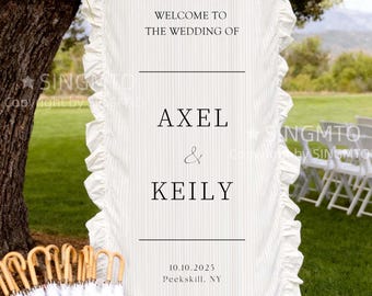Może przedstawiać: Biały znak powitalny na wesele z falbankami i pionowymi paskami. Na znaku widnieje napis "WELCOME TO THE WEDDING OF AXEL & KEILY" z datą 10.10.2025 i lokalizacją Peekskill, NY. Kosz białych parasoli znajduje się na pierwszym planie.