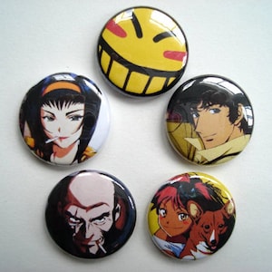 May include: A collection of five round pinback buttons featuring anime characters. The buttons display various characters in vibrant colors, including a yellow smiley face, and portraits of anime characters.