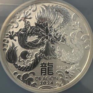 Może przedstawiać: Biały ceramiczny kubek z czarnym uchwytem i napisem "But First, Coffee" czarną, pogrubioną czcionką. Kubek stoi na białej powierzchni. Kubek ma około 10 cm wysokości.