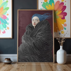 Może przedstawiać: Oprawiony wydruk artystyczny przedstawiający kobietę z niebieskimi włosami owiniętą w czarno-biały płaszcz w paski. Tło jest w kolorze głębokiego bordowego. W tle widoczne są dwa inne oprawione wydruki artystyczne z motywami kwiatowymi. Biały wazon z ozdobnymi łodygami stoi na podłodze.