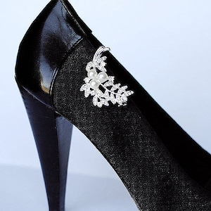 May include: Black high heel shoe with a silver and pearl embellishment on the side.