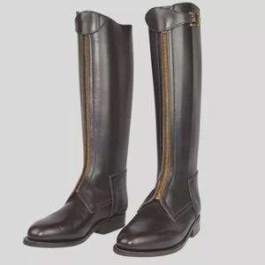 Puede incluir: Un par de botas de montar de color marrón oscuro. Las botas tienen una cremallera dorada en la parte delantera y una hebilla en la parte superior. Están hechas de cuero liso y tienen un tacón bajo. Miden unos 40 cm de alto.