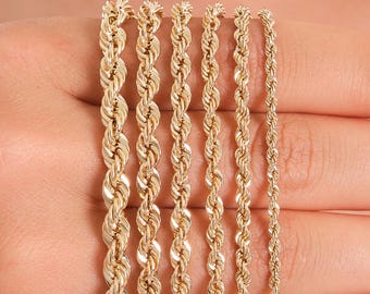 May include: A selection of gold rope chains of varying thicknesses. The chains are displayed against a neutral background, showcasing their intricate twisted design and warm, metallic color. The chains are a classic jewelry item.