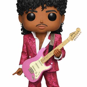 Może przedstawiać: Figurka winylowa Funko Pop przedstawiająca muzyka w różowym garniturze, trzymającego różową gitarę Fender Stratocaster. Figurka ma czarne kręcone włosy, wąsy i złoty kolczyk. Garnitur ma kwiatowy wzór. Figurka stoi na czarnej podstawie.