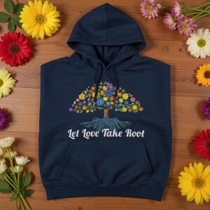 May include: Navy blue hoodie with a colorful tree design. The tree features a brown trunk, blue roots, and a vibrant crown of flowers in various colors. The text "Let Love Take Root" is printed below the tree.