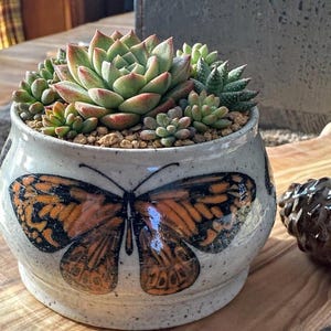 May include: A handmade wooden sign with the text "Welcome to our home" in a handwritten style. The sign is painted white with a dark stained frame. The sign measures approximately 12 inches wide and 8 inches tall.