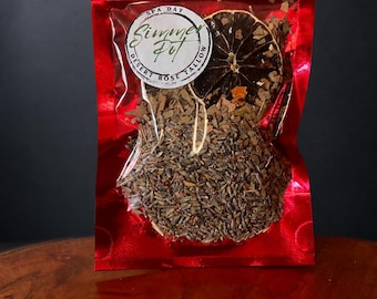 以下が含まれることがあります： 光沢のある赤いプラスチック製の袋に、乾燥したラベンダーの花、木片、乾燥した柑橘類の輪切りが入っています。前面の白い円形ラベルには「SPA DAY」、「Simmer Pot」、「DESERT ROSE TALLOW」という文字が黒いインクで印刷されています。