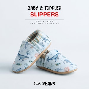 May include: Baby and toddler slippers featuring a light blue fabric with a pattern of whales, dolphins, sea turtles, coral, and bubbles. The slippers have a striped elastic cuff and a tan sole. Text reads: BABY & TODDLER SLIPPERS PDF SEWING PATTERN TUTORIAL 0-6 YEARS.