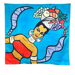 May include: A colourful pop art style wall hanging depicting a woman with a basket of fruit on her head. The artwork is set against a bright blue background with stylized, curved shapes. The woman is depicted in red, yellow, and black.