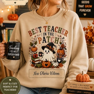 Puede incluir: Una sudadera beige de cuello redondo con un gráfico que incluye el texto BEST TEACHER IN THE PATCH, un fantasma con sombrero de bruja, calabazas y hojas de otoño. El diseño presenta un recuadro rectangular con el nombre Mrs Olivia Wilson.
