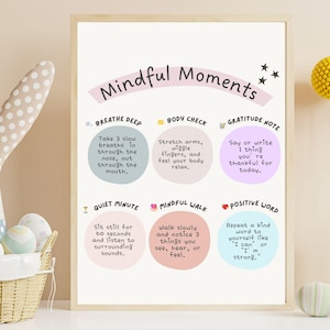 以下が含まれることがあります： 「Mindful Moments」の文字と、マインドフルネスの実践方法が書かれたフレーム入りのプリント。水玉模様の耳を持つぬいぐるみウサギと、装飾用の卵が入ったバスケットが手前にあります。