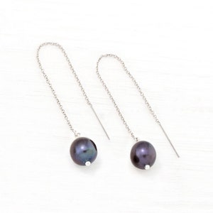 May include: A pair of silver chain earrings with black pearl drops.