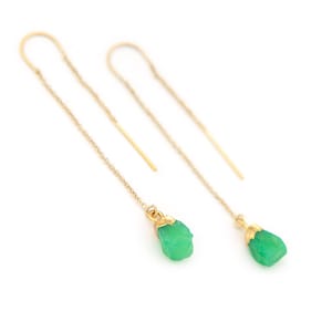 Puede incluir: Un par de pendientes de aro de oro con gotas de piedras preciosas verdes. Las piedras preciosas son en bruto y tienen una textura natural rugosa.