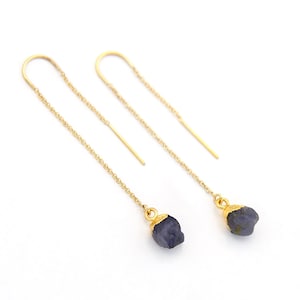 Puede incluir: Un par de pendientes de cadena dorada con una piedra preciosa azul oscuro colgando de cada cadena.