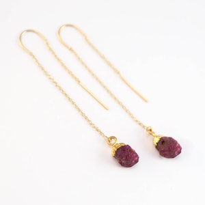 May include: A pair of gold chain earrings with a raw ruby gemstone dangling from each end.