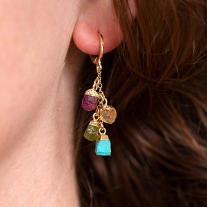 May include: Gold hoop earrings with a dangling cluster of four raw gemstones in shades of turquoise, green, yellow, and pink.