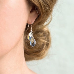 May include: Silver dangle earrings with blue and gold teardrop-shaped crystals.