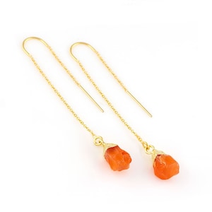 Puede incluir: Un par de pendientes de cadena dorada con gotas de piedra preciosa de cornalina naranja. La cornalina tiene una forma natural y rugosa.