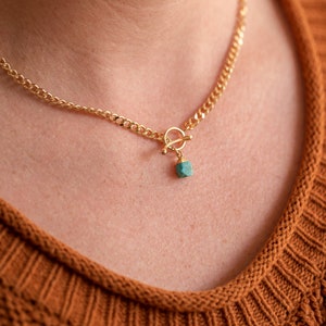 May include: A gold chain necklace with a turquoise stone pendant and a toggle clasp.