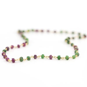 Może przedstawiać: Złoty naszyjnik z łańcuszkiem z naprzemiennymi zielonymi i fioletowymi koralikami z kamieni szlachetnych.