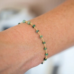 May include: A gold chain bracelet with small green gemstone beads.