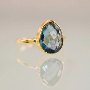 May include: A gold ring with a teardrop-shaped blue gemstone.