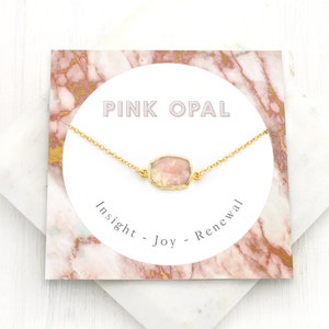 May include: A delicate gold chain necklace with a pink opal gemstone pendant. The card reads "Pink Opal - Insight - Joy - Renewal".