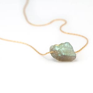 Pode incluir: Um delicado colar de corrente de ouro com um único pingente de pedra de labradorita bruta de cor verde claro.
