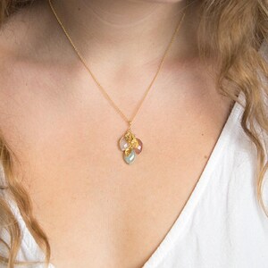 May include: A gold chain necklace with a pendant featuring a cluster of small, colorful gemstones. The pendant is made of gold and has a delicate, feminine design.