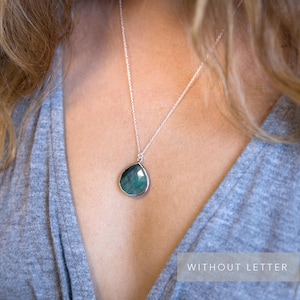 Pode incluir: Um colar de corrente de prata com um pingente de pedra preciosa verde em forma de l&aacute;grima.