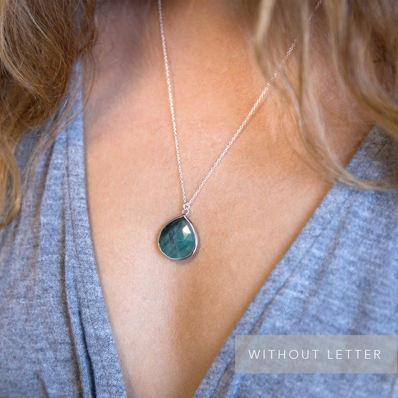 Pode incluir: Um colar de corrente de prata com um pingente de pedra preciosa verde em forma de l&aacute;grima.