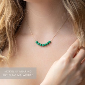 Puede incluir: Un collar de cadena de oro con una fila de siete cuentas de malaquita verde. El collar mide 40,6 cm de largo.  MODEL IS WEARING GOLD 16" MALACHITE