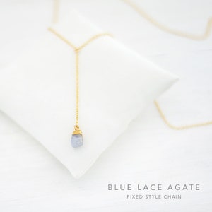 Puede incluir: Un delicado collar de cadena dorada con un colgante de &aacute;gata azul claro. El collar est&aacute; sobre una superficie blanca con el texto "BLUE LACE AGATE FIXED STYLE CHAIN".