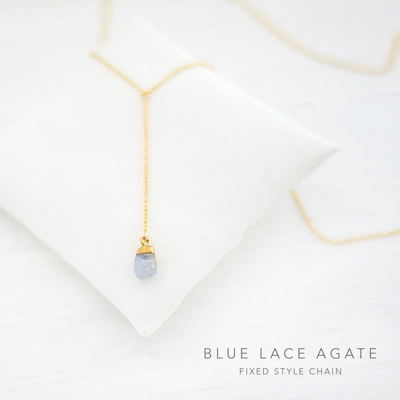 Puede incluir: Un delicado collar de cadena dorada con un colgante de &aacute;gata azul claro. El collar est&aacute; sobre una superficie blanca con el texto "BLUE LACE AGATE FIXED STYLE CHAIN".