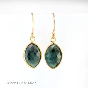 May include: A pair of gold earrings with a single, dark green gemstone in each earring. The gemstones are faceted and have a slightly oval shape.