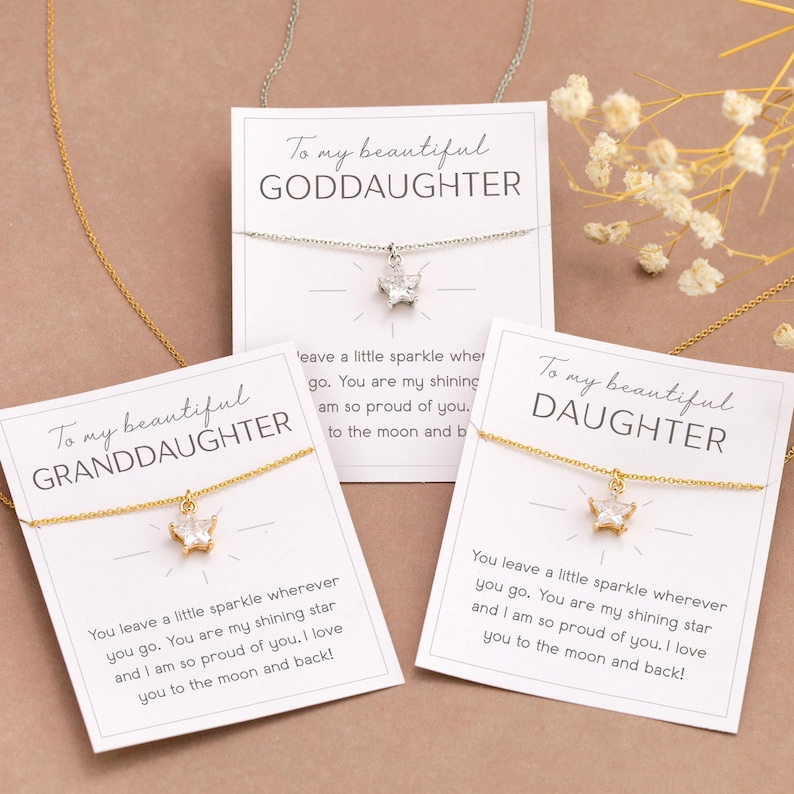 Puede incluir: Tres collares con tarjetas que dicen "To my beautiful GODDAUGHTER", "GRANDDAUGHTER" y "DAUGHTER". Cada collar tiene un peque&ntilde;o colgante. Las tarjetas tienen un mensaje sobre amor y orgullo.