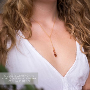 May include: A gold chain necklace with a long, dangling pendant made of small, orange-red stones. The necklace is 18 inches long with a 2 inch drop.