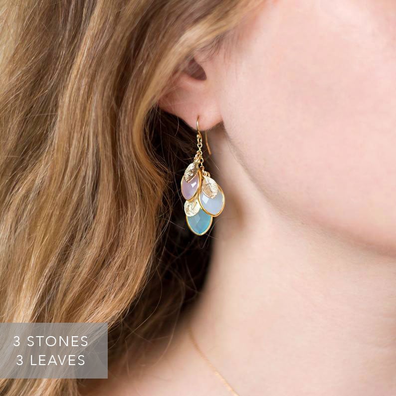 May include: Gold earrings with three teardrop-shaped stones in shades of blue and purple, and three gold leaves.