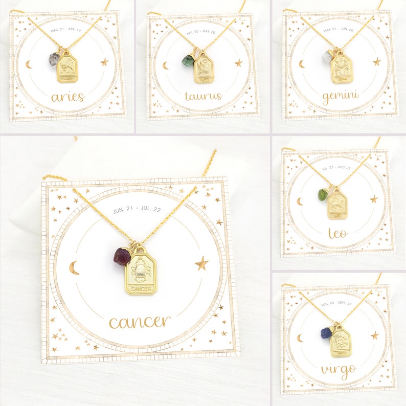 May include: Gold zodiac necklace with a gemstone charm on a white card with gold stars and a crescent moon. The card has the zodiac sign and dates for each sign. The signs shown are Aries, Taurus, Gemini, Cancer, Leo, and Virgo.