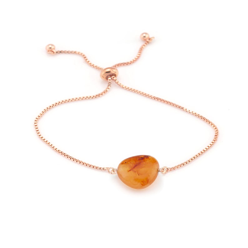 May include: A rose gold adjustable bracelet with a single amber gemstone pendant.