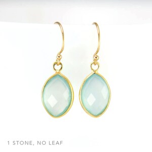May include: A pair of gold earrings with light blue gemstone drops. The earrings have a simple design with a single stone on each earring.