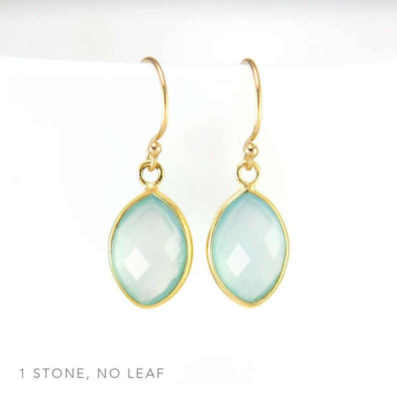 May include: A pair of gold earrings with light blue gemstone drops. The earrings have a simple design with a single stone on each earring.