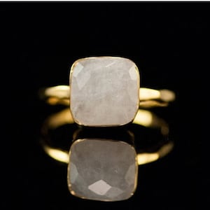Puede incluir: Un anillo de oro con una piedra blanca de forma cuadrada.