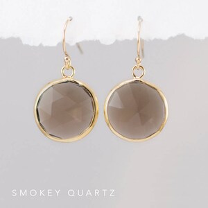 May include: A pair of gold dangle earrings with smoky quartz stones. The stones are round and faceted.